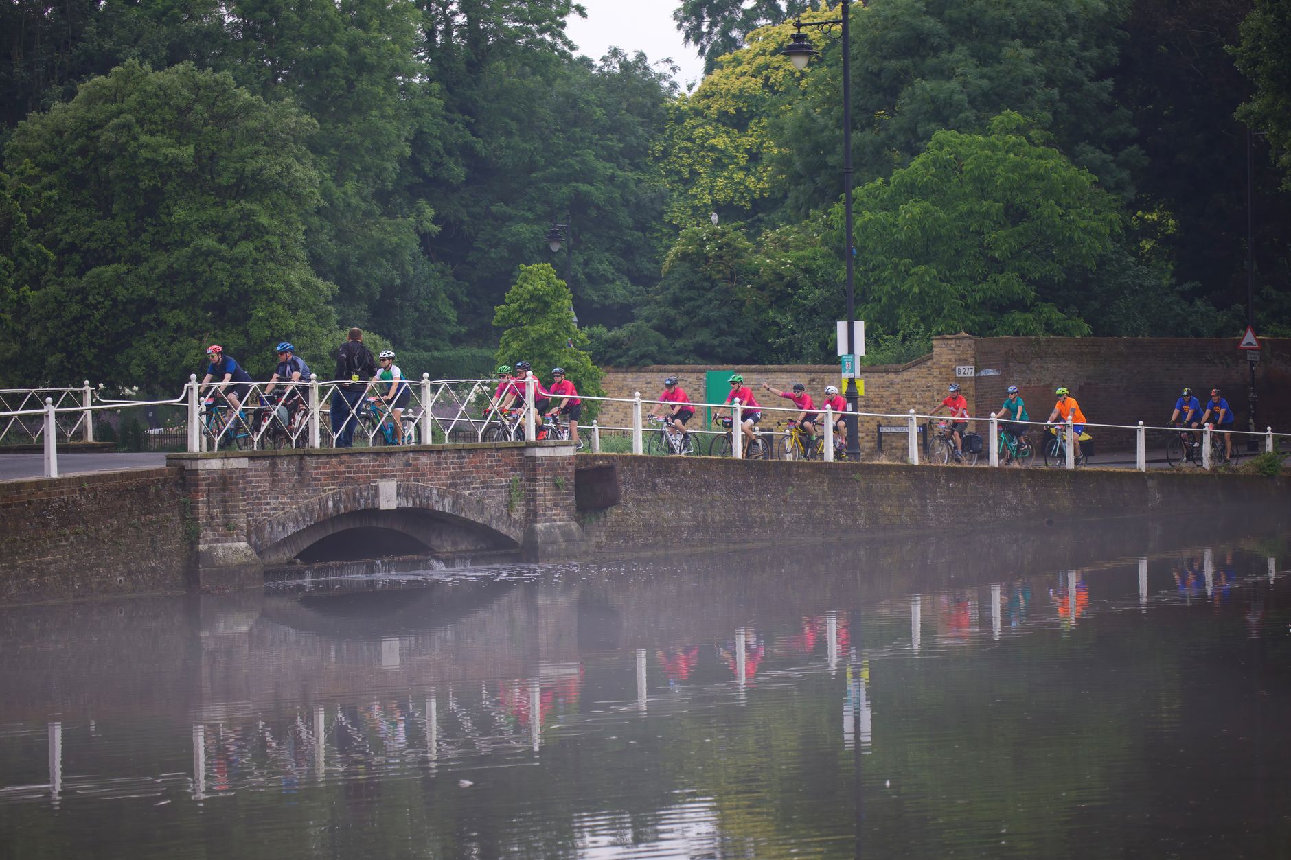 Cyclists riding along the Naviglio Grande towpath at golden hour with canal-side bars and umbrellas