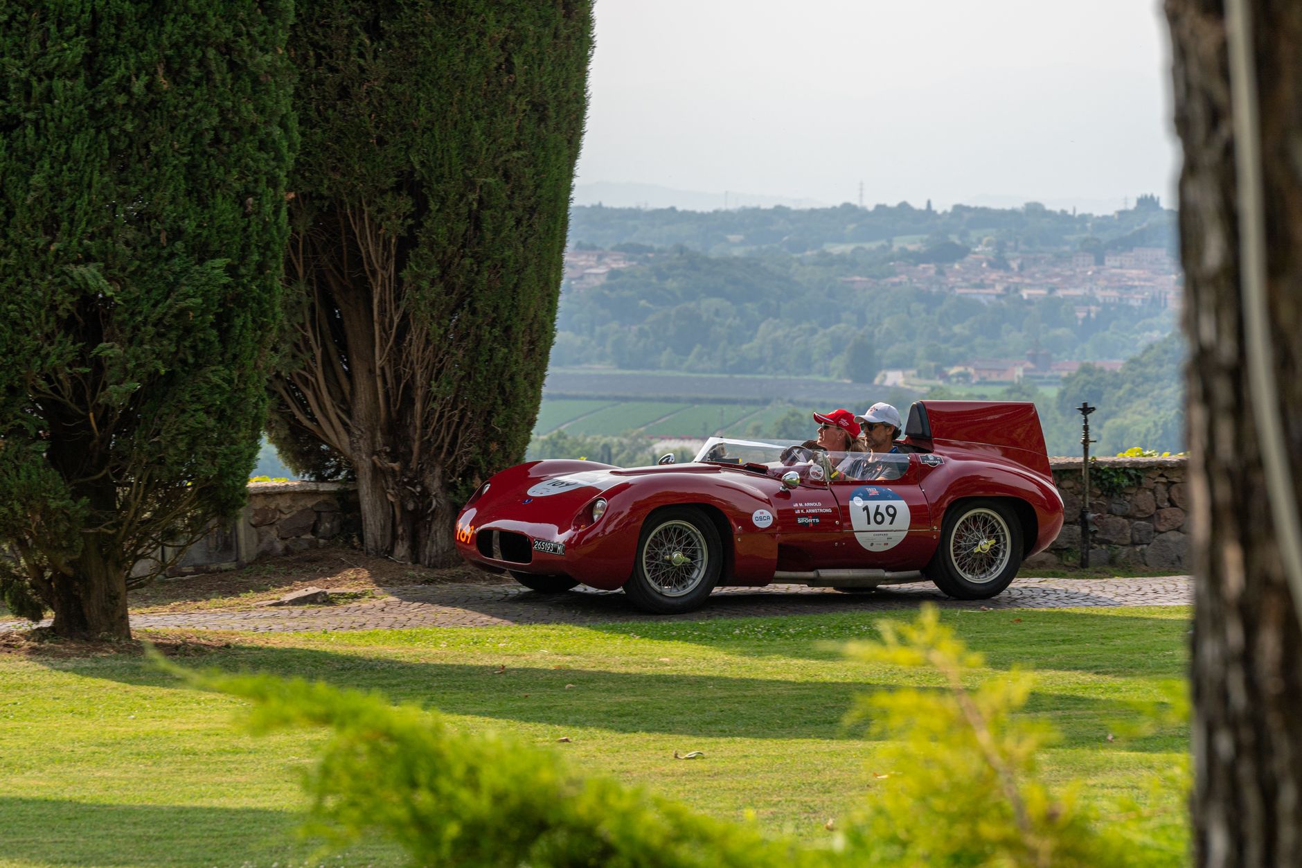Mille Miglia classic cars passing through Milan city center at dusk