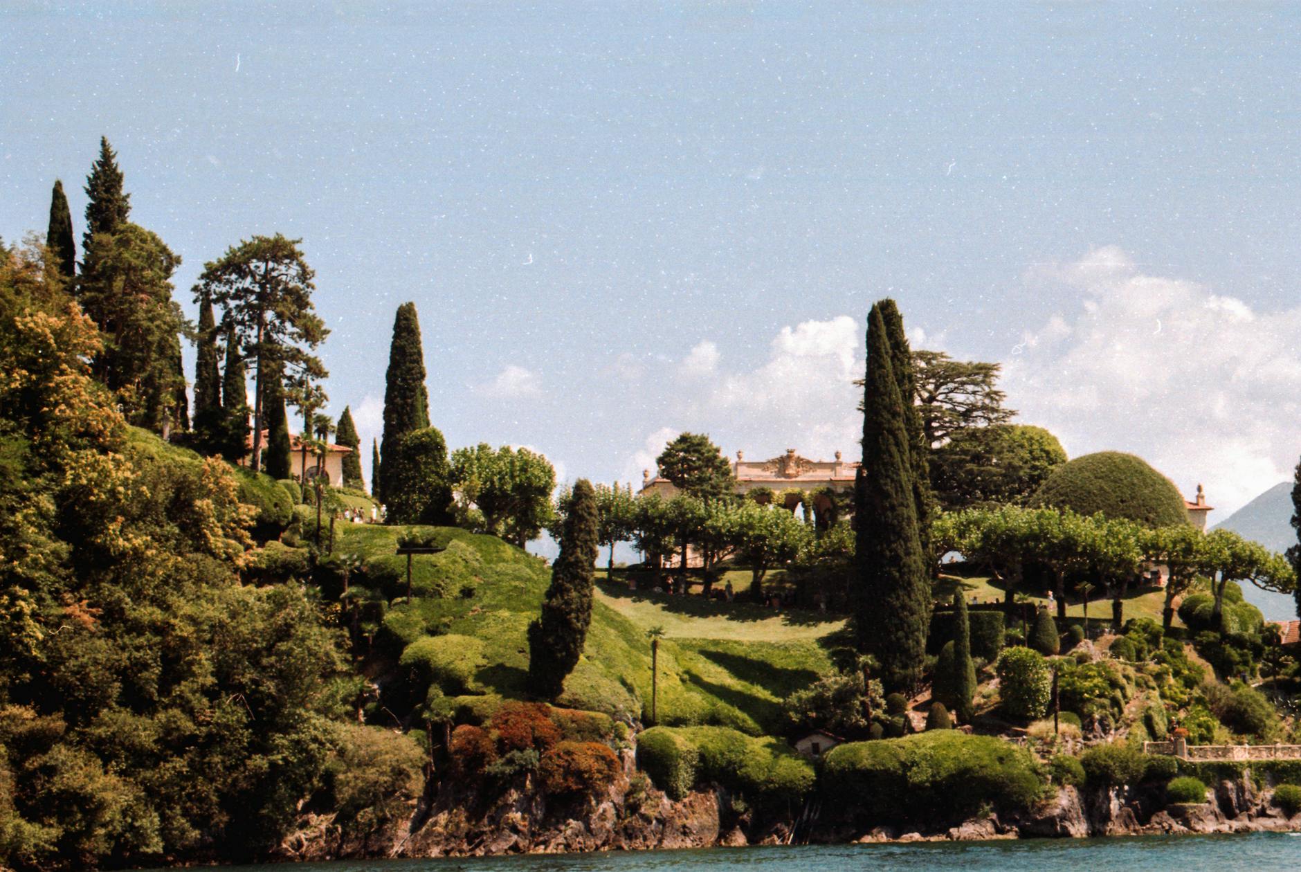 Villa del Balbianello promontory jutting into Lake Como with cypress trees and classical garden, viewed from a boat