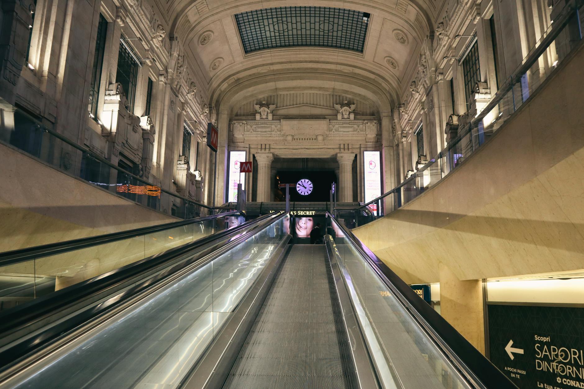 Milano Centrale station interior, traveler at left luggage counter with backpack