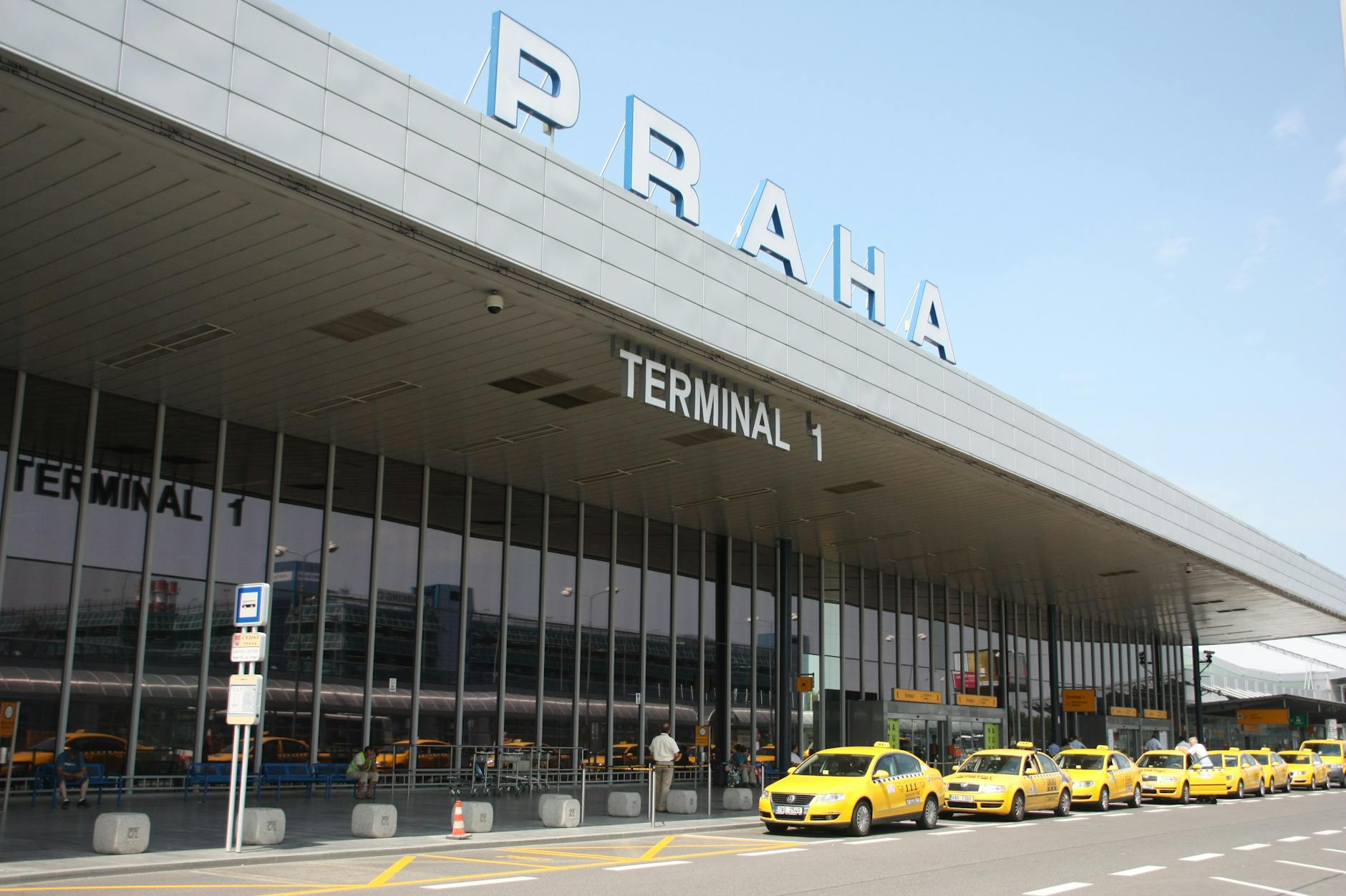 Taxi at Malpensa Terminal 1 curbside drop-off with passenger loading luggage