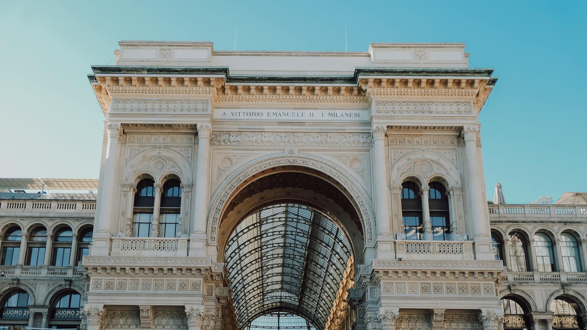 Milano Centrale facade with the morning sun on the carved stone reliefs, taxis queued out front