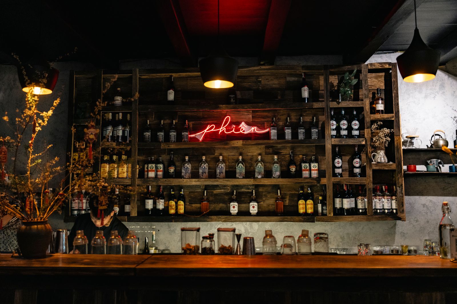 Dimly lit speakeasy-style cocktail bar with a red neon glow, the kind found around Brera in Milan